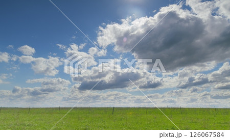 A Vibrant Green Field beautifully spreads out majestically under a dramatic, cloudy sky above it Time lapse. 126067584