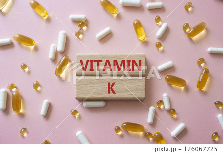 Vitamin K symbol. Concept word Vitamin K on wooden blocks. Beautiful pink background with pills. Medicine and Vitamin K concept. Copy space Vitamin K symbol. Concept word Vitamin K on wooden blocks. Beautiful pink background with pills. Medicine and Vitamin K concept. Copy space 126067725