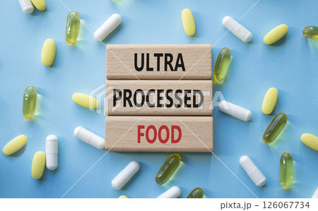 Medicine symbol. Concept words Ultra Processed Food on wooden blocks. Beautiful blue background with pills. Medicine concept and Ultra Processed Food. Copy space Medicine symbol. Concept words Ultra Processed Food on wooden blocks. Beautiful blue background with pills. Medicine concept and Ultra Processed Food. Copy space 126067734