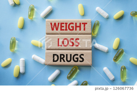Medicine symbol. Concept words Weight Loss Drugs on wooden blocks. Beautiful blue background with pills. Medicine concept and Weight Loss Drugs. Copy space Medicine symbol. Concept words Weight Loss Drugs on wooden blocks. Beautiful blue background with pills. Medicine concept and Weight Loss Drugs. Copy space 126067736