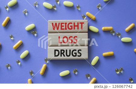 Medicine symbol. Concept words Weight Loss Drugs on wooden blocks. Beautiful purple background with pills. Medicine concept and Weight Loss Drugs. Copy space 126067742