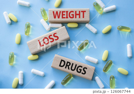 Medicine symbol. Concept words Weight Loss Drugs on wooden blocks. Beautiful blue background with pills. Medicine concept and Weight Loss Drugs. Copy space 126067744