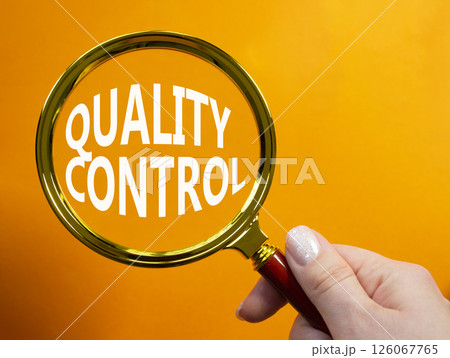 Quality Control symbol. Magnifying glass with words Quality Control. Beautiful orange background. Businessman hand. Business and Quality Control concept. Copy space. 126067765