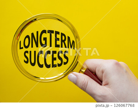 Longterm success symbol. Magnifying Glass with Concept word Longterm success. Businessman hand. Beautiful yellow background. Business and Longterm success concept. Copy space Longterm success symbol. Magnifying Glass with Concept word Longterm success. Businessman hand. Beautiful yellow background. Business and Longterm success concept. Copy space 126067768