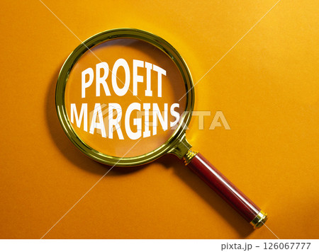 Profit Margins symbol. Magnifying glass with words Profit Margins. Beautiful orange background. Business and Profit Margins concept. Copy space. 126067777
