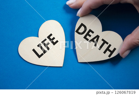 Life or Death symbol. Concept word Life or Death on wooden hearts. Businessman hand. Beautiful blue background. Business and Life or Death concept. Copy space 126067819