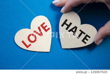 Love vs Hate symbol. Concept word Love vs Hate on wooden hearts. Businessman hand. Beautiful blue background. Business and Love vs Hate concept. Copy space 126067820