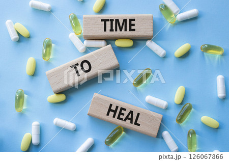 Medicine symbol. Concept words Time to Heal on wooden blocks. Beautiful blue background with pills. Medicine concept and Time to Heal. Copy space Medicine symbol. Concept words Time to Heal on wooden blocks. Beautiful blue background with pills. Medicine concept and Time to Heal. Copy space 126067866