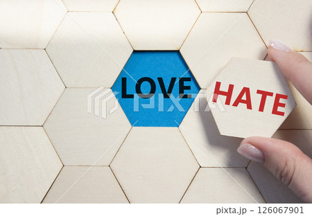 Love vs Hate symbol. Concept word Love vs Hate on wooden comb puzzle. Businessman hand. Beautiful blue background. Business and Love vs Hate concept. Copy space Love vs Hate symbol. Concept word Love vs Hate on wooden comb puzzle. Businessman hand. Beautiful blue background. Business and Love vs Hate concept. Copy space 126067901