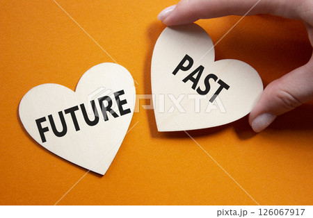 Future or Past symbol. Concept word Future or Past on wooden hearts. Businessman hand. Beautiful orange background. Business and Future or Past concept. Copy space 126067917