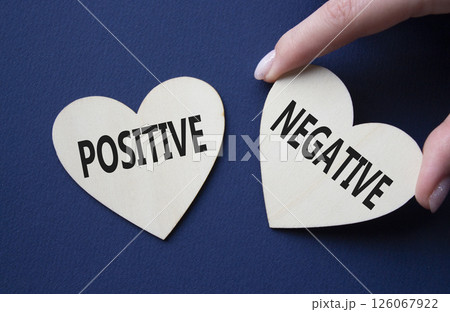 Positive or Negative symbol. Concept word Positive or Negative on wooden hearts. Businessman hand. Beautiful deep blue background. Business and Positive or Negative concept. Copy space 126067922