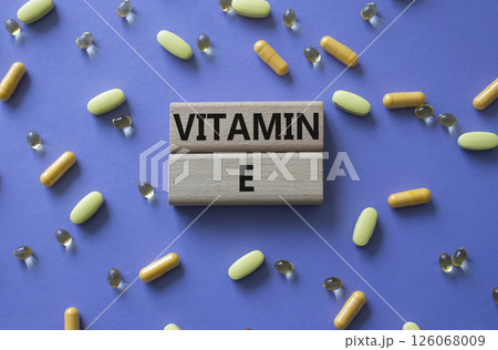 Vitamin E symbol. Concept word Vitamin E on wooden blocks. Beautiful purple background with pills. Medicine and Vitamin E concept. Copy space 126068009