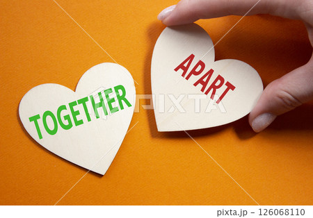 Together or Apart symbol. Concept word Together or Apart on wooden hearts. Businessman hand. Beautiful orange background. Business and Together or Apart concept. Copy space Together or Apart symbol. Concept word Together or Apart on wooden hearts. Businessman hand. Beautiful orange background. Business and Together or Apart concept. Copy space 126068110