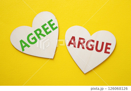 Agree or Argue symbol. Concept word Agree or Argue on wooden hearts. Beautiful yellow background. Business and Agree or Argue concept. Copy space 126068126