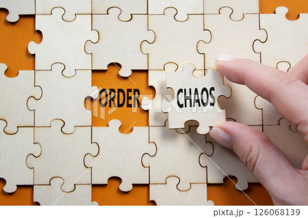 Chaos or Order symbol. Concept word Chaos or Order on wooden puzzle. Businessman hand. Beautiful orange background. Business and Chaos or Order concept. Copy space 126068139