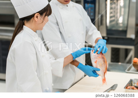 魚を調理するコックコート姿の男女スタッフ（調理師・料理人・生鮮市場・食品加工） 126068388