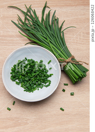 Fresh chives bundle and chopped pieces on wooden surface Fresh chives bundle and chopped pieces on wooden surface 126068422