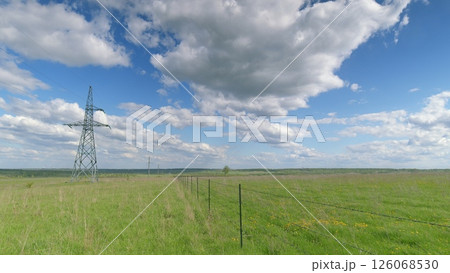 A picturesque landscape with an electric tower in a vast field of vibrant greenery Time lapse. A picturesque landscape with an electric tower in a vast field of vibrant greenery Time lapse. 126068530