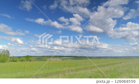 A stunning and captivating panoramic landscape features a bright blue sky and vibrant green fields Time lapse. 126068550