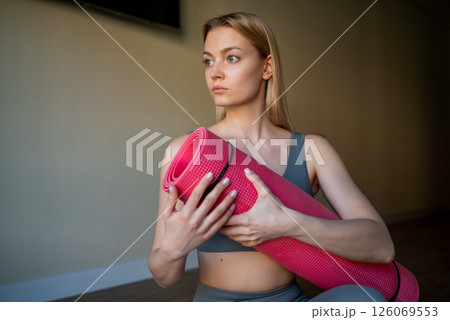 Home workout of a beautiful woman. Home workout on the gym mat in the living room, athletic woman in sports clothes 126069553