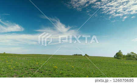A Vast and Lush Green Field Enjoying the Warmth of a Clear and Bright Blue Sky Above 126070680