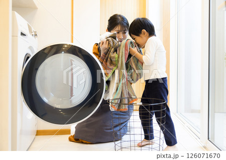 ドラム式洗濯機から洗濯物を取り出す親子 126071670