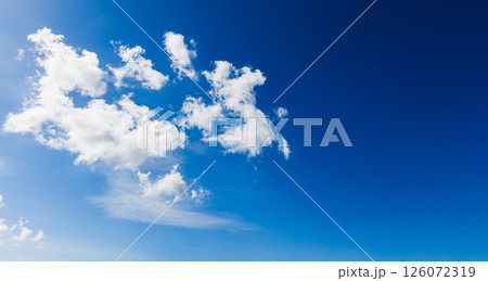 A serene blue sky adorned with white, fluffy clouds floating tranquilly 126072319