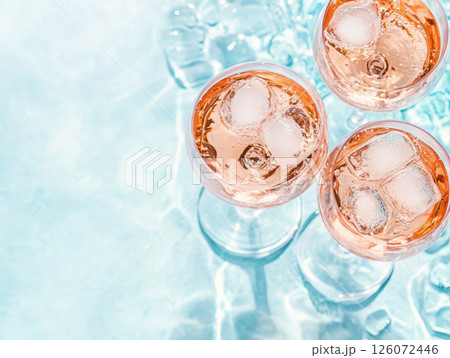 Chilled rose wine glasses with ice above bright pool surface, creating refreshing summer vibe. Perfect for relaxation and enjoyment 126072446