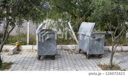 Garbage containers on an asphalt near by houses 126072823