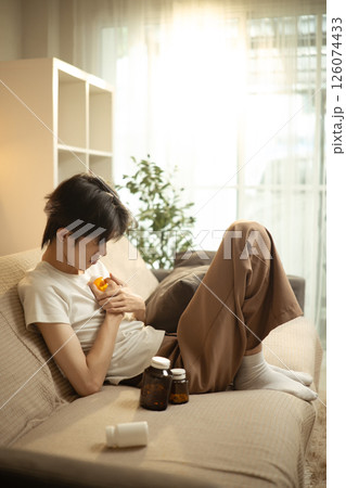 Man dealing with emotional pain and depression at home surrounded by medication 126074433