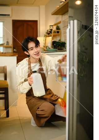 Man wearing an apron grabbing ingredients to prepare breakfast at home 126074434