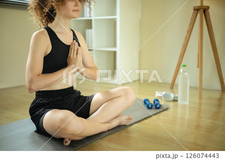 Young Russian woman with curly hair practicing yoga at home 126074443