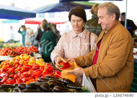 Aged man and woman customers buying pepper in open-air market 126074690