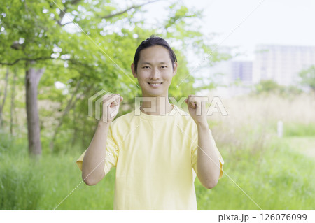 公園に立つ両手でガッツポーズをする若い男性のポートレート 公園に立つ両手でガッツポーズをする若い男性のポートレート 126076099