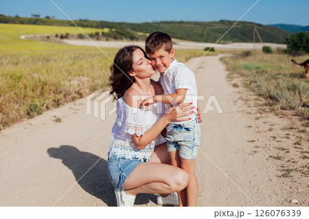 Mother with son walking in a rural field in summer by the road 126076339