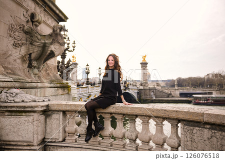 Woman sitting on stone railing of historic bridge.05.04.2025 Paris France Woman sitting on stone railing of historic bridge.05.04.2025 Paris France 126076518
