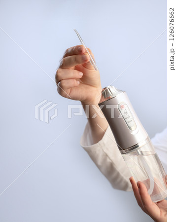Modern oral hygiene: a woman uses an irrigator to remove plaque and food particles, maintaining dental health. 126076662