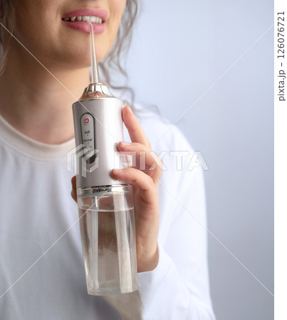 Following dentist advice woman uses water flosser for thorough teeth cleaning after sleep as part of her healthy morning routine. 126076721