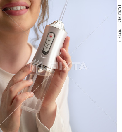 Clean teeth and a fresh start to the day: woman removes food debris and plaque with a water flosser. 126076751