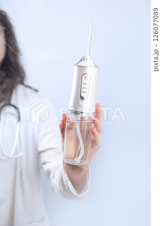 Female dentist explains how to use an oral irrigator which tips to choose and why daily water cleaning is essential for oral health. 126077089