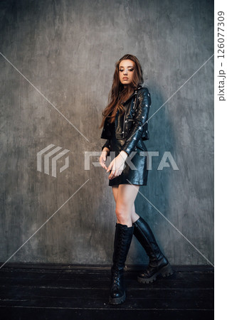 Beautiful woman in black leather dress in gray room interior 126077309