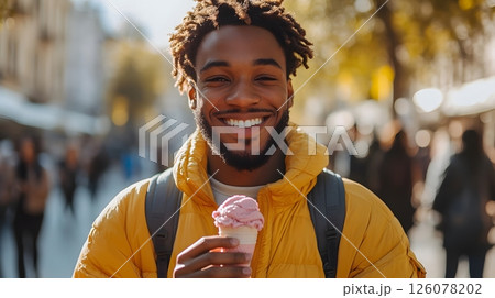 smiling man eating pink ice cream and checking smartphone in sunny public park while people jog and relax nearby 126078202