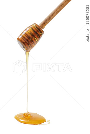 wooden honey dipper with golden honey dripping 126078583
