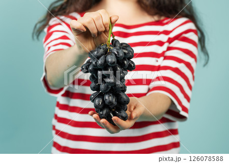 Close-up of young woman holding black grapes 126078588