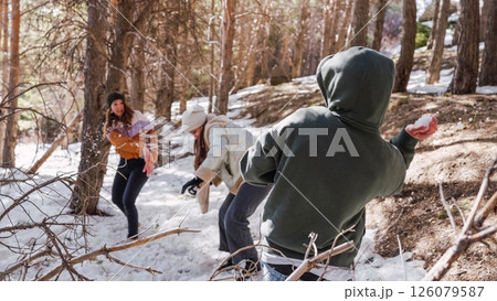 Friends throwing snowballs, enjoying winter fun in snowy forest 126079587
