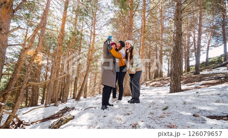 Friends taking selfie in snowy forest during winter hike 126079657
