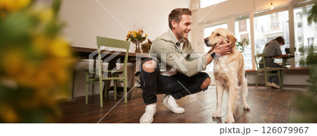 Close up portrait of happy dog owner, man with his pet giving a treat, spending time in animal-friendly cafe or co-working space Close up portrait of happy dog owner, man with his pet giving a treat, spending time in animal-friendly cafe or co-working space 126079967