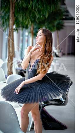 Elegant ballerina in black tutu posing gracefully with hand near face 126080000