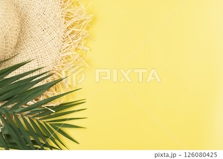 Vacation travel planning simple theme of straw hat and palm leaves on uniform yellow background flat lay with copy-space 126080425