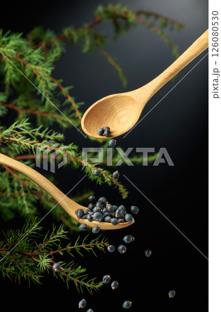Juniper seeds are sprinkled with a wooden spoon. Juniper seeds are sprinkled with a wooden spoon. 126080530